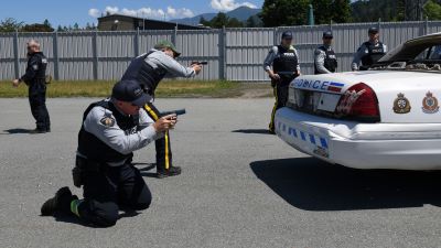 Un policier se tient à genoux et un autre est debout à côté de lui. Ils pointent leurs armes à feu dans le cadre d’un scénario de pratique.