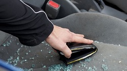 Broken glass on car seat, arm reaching in to grab a wallet
