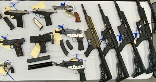 Multiple types of firearms laying on a table