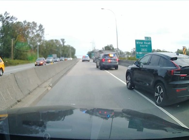 Rear view of dump truck pulled over on the right-hand side of the highway, with a police vehicle both in front and behind it