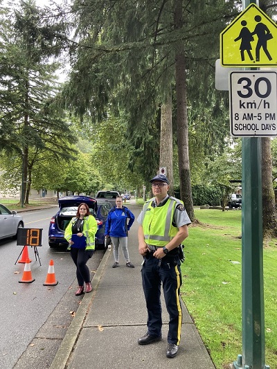 Un agent de la GRC et un membre de la police communautaire font respecter la vitesse dans une zone scolaire au moyen d’un panneau indiquant une vitesse de 30 km/h en haut à droite.