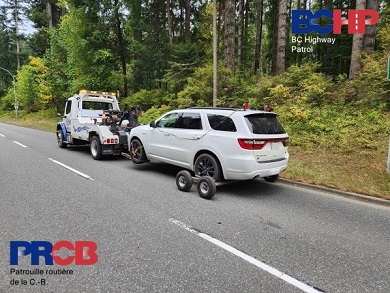 Side view of white Dodge Durango hooked up to the back of a tow truck