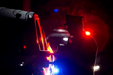 Nighttime silhouette of police officer with red and blue lights in the background