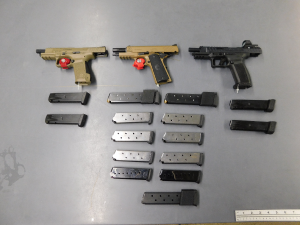 Three semi-automatic handguns two tan and one black, with several magazines on a table