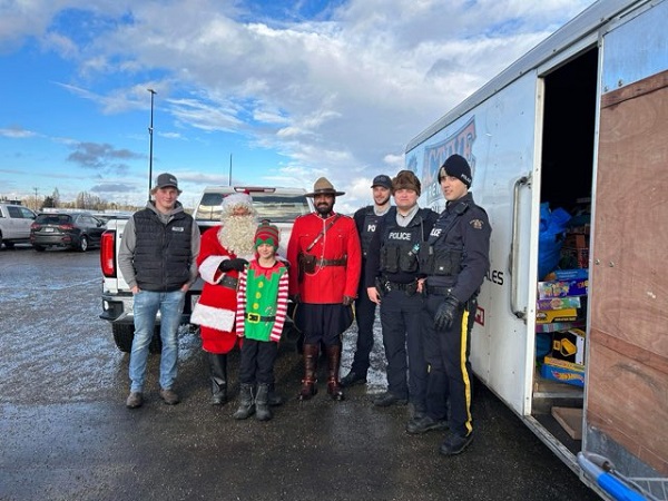 Four police officers standing with Santa, an elf and a man donating items