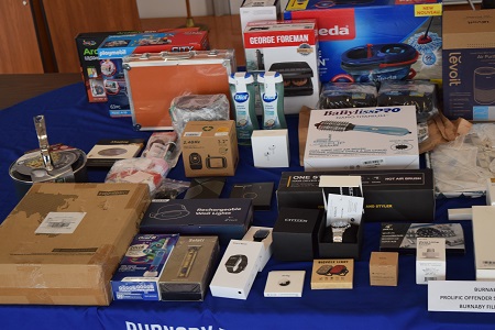 Various stolen items laid out on a table with a blue table cloth, including personal hygiene items and watches.