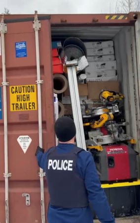 Police officer opening a container full of stolen merchandise.