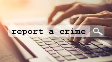 Mains sur un clavier et un champ de recherche où il est indiqué « signalement d’un crime »